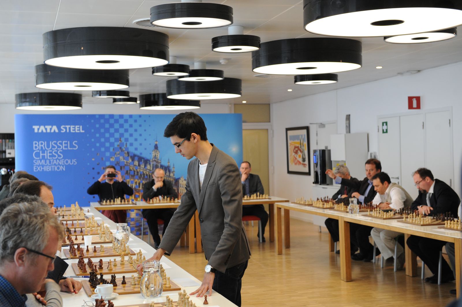 Anish Giri playing a simultaneous exhibition against players seated around a room
